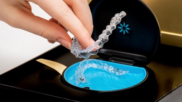 Person placing a clear aligner into its storage case