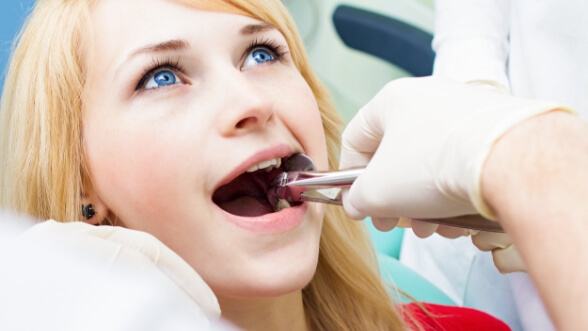 Young blonde woman having a tooth removed