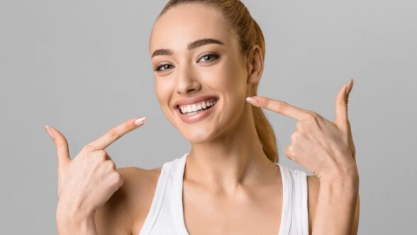 Woman pointing to her grin after cosmetic dentistry in Mississauga