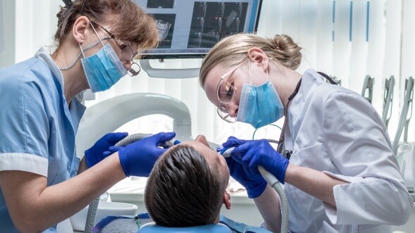 Two dentists treating a patient